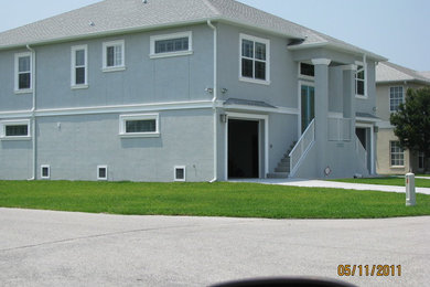 Imagen de fachada gris grande de dos plantas con revestimiento de estuco y tejado a cuatro aguas