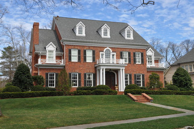 Large elegant red three-story brick exterior home photo in Other