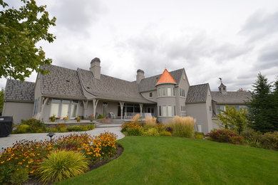 Diseño de fachada beige tradicional grande de dos plantas con revestimiento de estuco y tejado a dos aguas