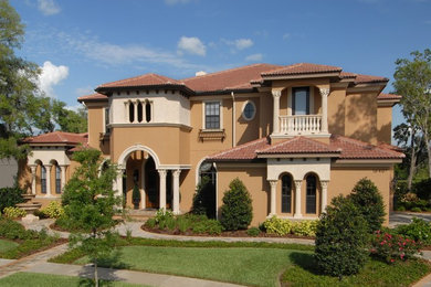 Large mediterranean brown two-story stucco house exterior idea in Tampa with a hip roof and a tile roof
