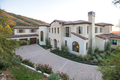 Large tuscan beige two-story stucco exterior home photo with a hip roof