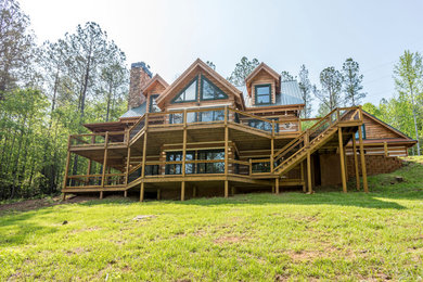 Foto de fachada de casa marrón rústica grande de dos plantas con revestimiento de madera, tejado a dos aguas y tejado de metal