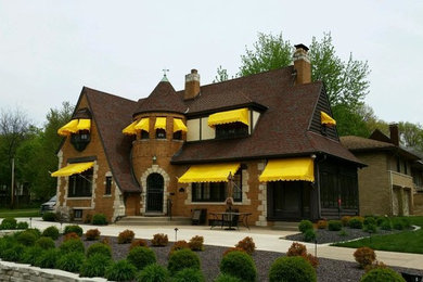 Ejemplo de fachada de casa multicolor grande de dos plantas con revestimiento de ladrillo, tejado a dos aguas y tejado de teja de madera