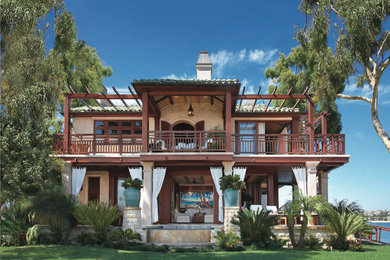Imagen de fachada beige tropical grande de dos plantas con revestimiento de estuco y tejado a cuatro aguas