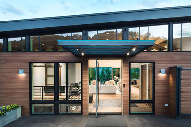 Diseño de fachada de casa multicolor actual grande de dos plantas con revestimientos combinados y tejado de metal