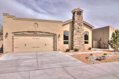 Example of a small tuscan brown one-story stucco flat roof design in Albuquerque