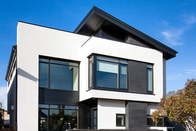 Diseño de fachada de casa blanca contemporánea de tamaño medio de dos plantas con revestimientos combinados y tejado de teja de madera