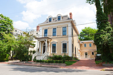 Foto della facciata di una casa piccola gialla vittoriana a due piani con rivestimenti misti