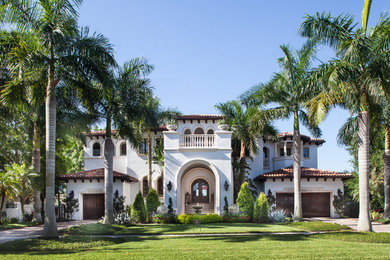 Example of a mid-sized tuscan white two-story stucco house exterior design in Tampa with a hip roof and a tile roof
