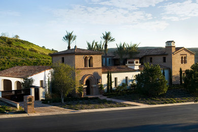 Idee per la villa multicolore mediterranea a due piani con rivestimento in mattoni, falda a timpano e copertura in tegole