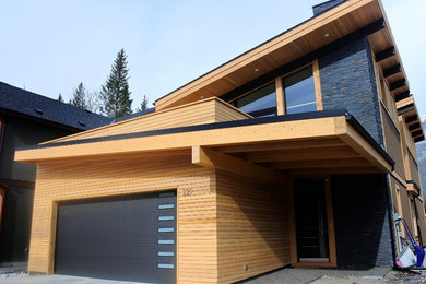 This is an example of a medium sized and brown modern two floor detached house in Calgary with wood cladding and a lean-to roof.