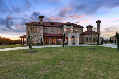 Huge mediterranean beige two-story stone house exterior idea in Dallas with a tile roof