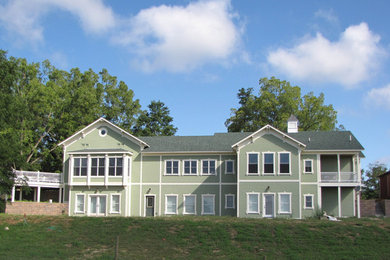 На фото: большой, двухэтажный, зеленый дом в классическом стиле с облицовкой из ЦСП и двускатной крышей с