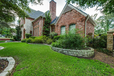 Inspiration for a large timeless beige two-story brick exterior home remodel in Dallas with a clipped gable roof