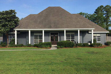 This is an example of a medium sized and gey traditional bungalow render detached house in New Orleans with a hip roof and a shingle roof.