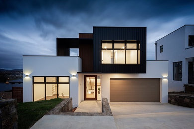 Imagen de fachada de casa blanca minimalista de tamaño medio de tres plantas con revestimiento de estuco, tejado plano y tejado de metal