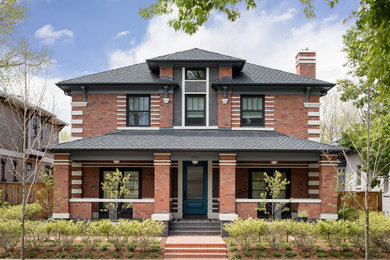 Inspiration for a timeless red two-story brick house exterior remodel in Denver with a hip roof and a shingle roof