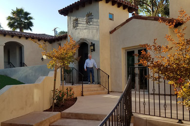 Example of a large tuscan beige two-story stucco house exterior design in San Diego with a hip roof and a tile roof