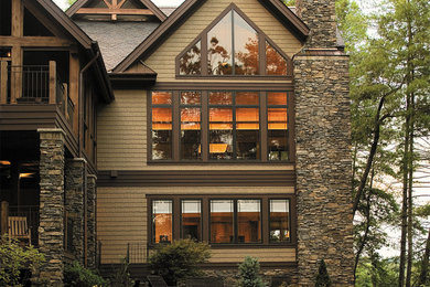 Ejemplo de fachada de casa marrón rústica grande de dos plantas con revestimiento de madera, tejado a dos aguas y tejado de teja de madera