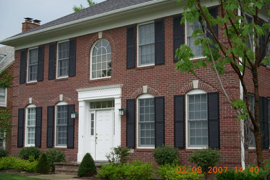 Example of a mid-sized classic red two-story brick exterior home design in Cleveland with a hip roof