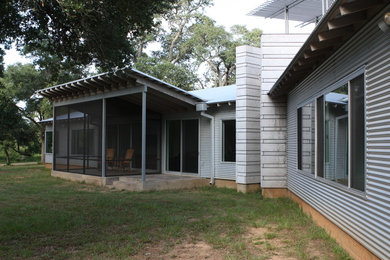 Diseño de fachada de casa gris actual de tamaño medio de una planta con revestimiento de metal, tejado de un solo tendido y tejado de metal