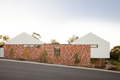 Imagen de fachada de casa contemporánea de dos plantas con revestimiento de ladrillo y tejado a dos aguas