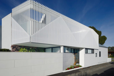 Diseño de fachada de casa blanca actual pequeña de dos plantas con revestimiento de metal, tejado plano y tejado de metal