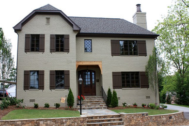 Esempio della facciata di una casa beige classica a due piani di medie dimensioni con rivestimento in mattoni e tetto a padiglione