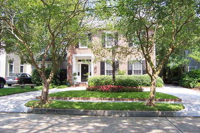 Example of a mid-sized classic red two-story brick exterior home design in New Orleans with a clipped gable roof