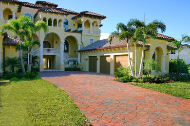 Inspiration for a huge tropical yellow three-story exterior home remodel in Tampa with a hip roof