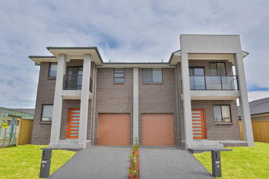 Modelo de fachada de casa bifamiliar multicolor contemporánea de tamaño medio de dos plantas con revestimiento de ladrillo, tejado a cuatro aguas y tejado de teja de barro