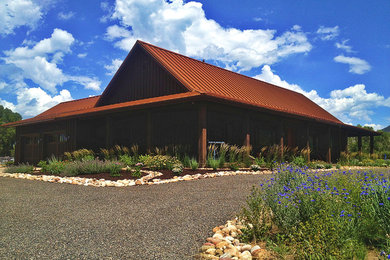 Cette image montre une façade de maison marron sud-ouest américain en bois de taille moyenne et de plain-pied avec un toit à deux pans et un toit en métal.