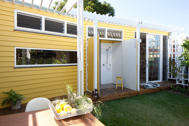Design ideas for a small and yellow bohemian bungalow house exterior in Sydney with concrete fibreboard cladding and a flat roof.