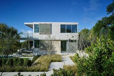 Modelo de fachada de casa beige costera de dos plantas con revestimientos combinados y tejado plano