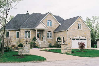 Imagen de fachada de casa beige clásica grande de dos plantas con revestimiento de piedra, tejado a dos aguas y tejado de teja de madera