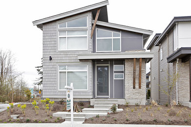 Foto de fachada gris actual de tamaño medio de tres plantas con revestimientos combinados