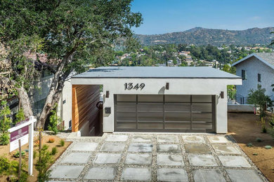 Ejemplo de fachada de casa gris minimalista de tamaño medio a niveles con revestimiento de estuco, tejado plano y tejado de varios materiales