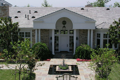 Imagen de fachada blanca tradicional grande de dos plantas con revestimiento de piedra y tejado a dos aguas