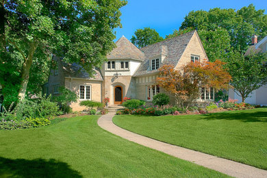 Large elegant beige two-story brick house exterior photo in Grand Rapids with a tile roof