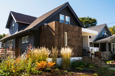 Réalisation d'une façade de maison noire minimaliste en bois à un étage avec un toit plat.