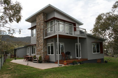 На фото: двухэтажный, деревянный, серый дом среднего размера в современном стиле с двускатной крышей