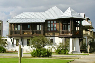 Photo of a medium sized and multi-coloured world-inspired two floor detached house with wood cladding, a hip roof and a metal roof.