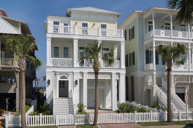 Exemple d'une façade de maison jaune bord de mer en bois à deux étages et plus avec un toit à quatre pans et un toit en métal.