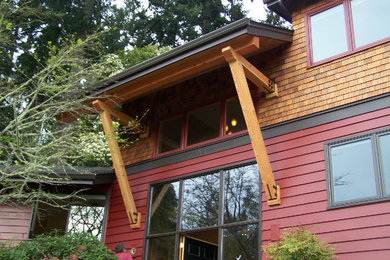 Large mountain style red two-story wood exterior home photo in Portland
