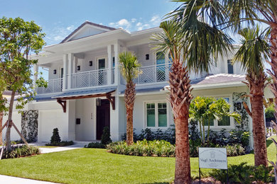 Ejemplo de fachada de casa azul tropical grande de dos plantas con revestimiento de estuco, tejado a cuatro aguas y tejado de varios materiales