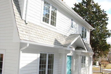 Modelo de fachada de casa blanca clásica renovada de tamaño medio de dos plantas con revestimiento de madera, tejado a dos aguas y tejado de teja de madera