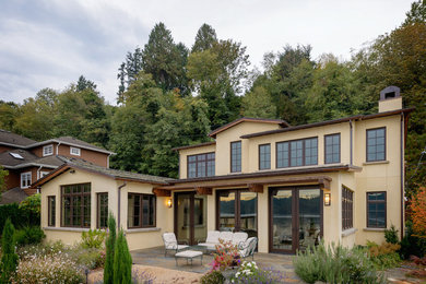 Aménagement d'une façade de maison beige méditerranéenne en stuc de taille moyenne et à un étage avec un toit à deux pans.