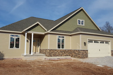 Exemple d'une façade de maison beige chic de taille moyenne et de plain-pied avec un revêtement mixte et un toit à quatre pans.