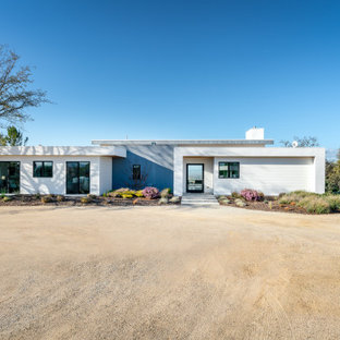 Foto de fachada de casa amarilla, contemporánea, de tamaño medio, de una planta, con revestimiento de aglomerado de cemento y tejado de un solo tendido