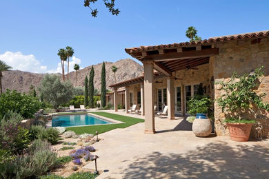 Inspiration for a large southwestern beige one-story stone gable roof remodel in Other with a shingle roof